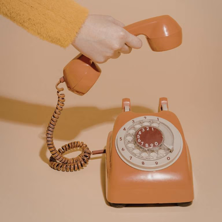 hand hanging up a rotary phone